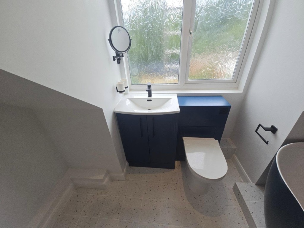 Steel-blue basin and toilet unit under the window