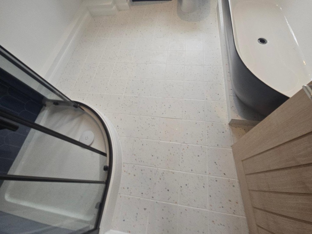 Speckled floor tiles beside the freestanding bath