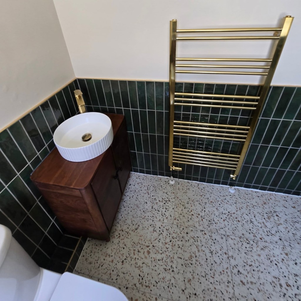 Ribbed basin on a walnut vanity beside a gold heated towel rail