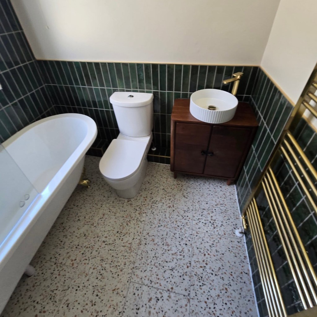 Toilet, walnut vanity and gold towel rail in the finished bathroom