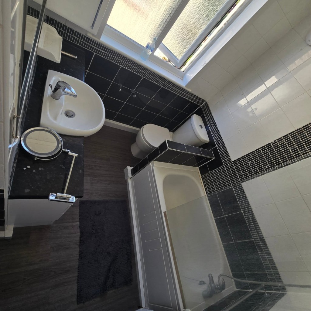 The old suite from above, with a black vanity, toilet and bath under the window