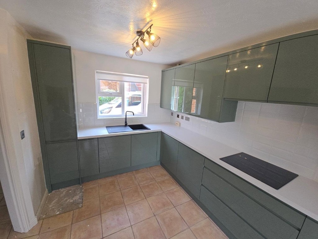 Black sink and tap under the window, with the tall cabinet beside the doorway