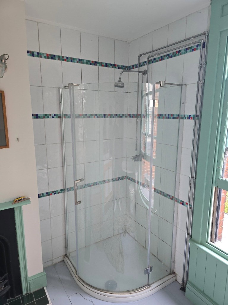 The old quadrant shower, with exposed pipework and a mosaic tile border